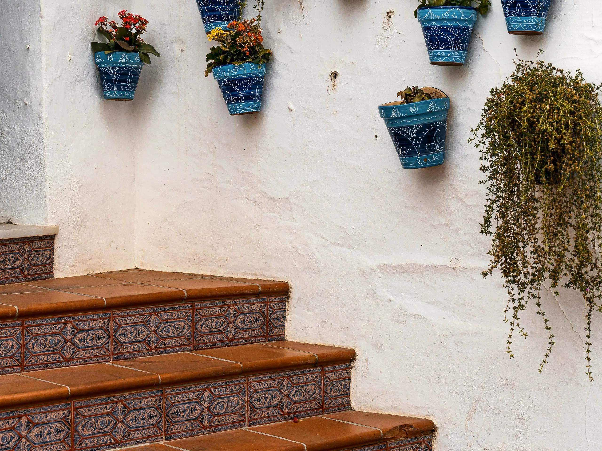 Biela stena s modrobielymi kvetináčmi pri vstupe do domu